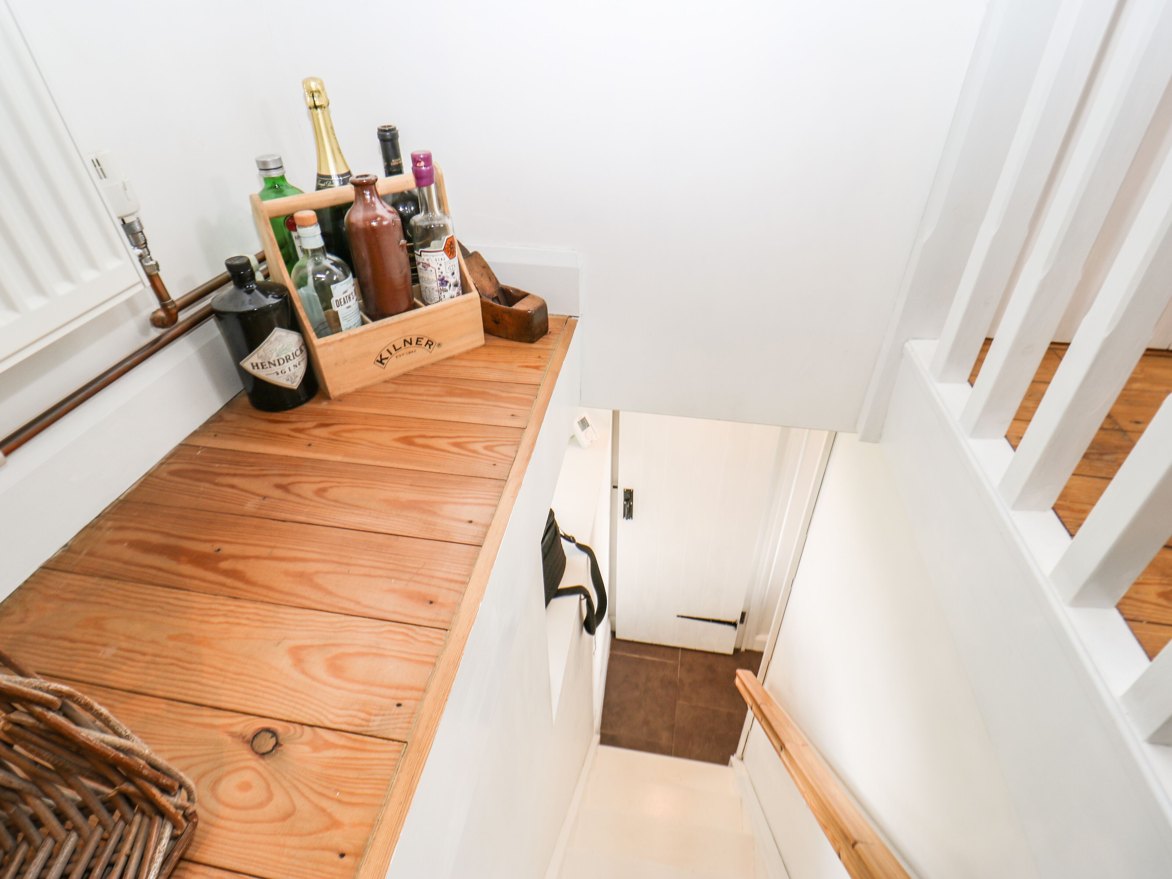 Un escalier en bois, avec une petite boîte en bois contenant des bouteilles, est placé sur le palier.