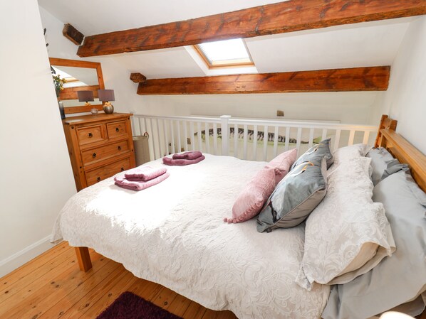 A bedroom with a bed, wooden dresser, and a skylight. - The Mistle Carr Farm (Sowerby Bridge)