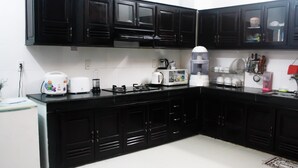A kitchen with black cabinets, white appliances, and a tiled backsplash. - Hana Homestay Danang (Da Nang)