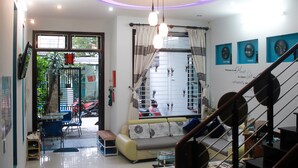 A modern living room with a sofa, coffee table, and a staircase. - Hana Homestay Danang (Da Nang)
