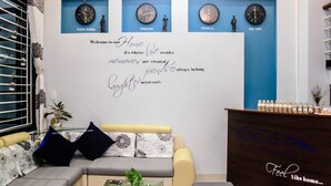 A modern living room with a sofa, a coffee table, and a decorative wall with clocks and a motivational quote. - Hana Homestay Danang (Da Nang)