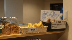 A breakfast bar with jars of cereal, a basket of bananas, and a sign indicating free margarine and jam. - Hana Hostel Fujisan (Fujiyoshida)