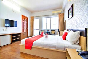 Een hotelkamer met een bed, een bureau, een televisie, een raam en een stoel.