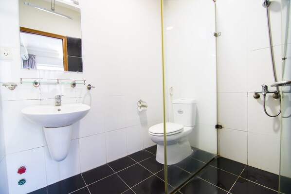 Een badkamer met een witte wastafel, toilet en douche.