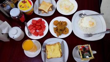 Una mesa con alimentos para el desayuno, como tostadas, huevos, arroz y fruta.