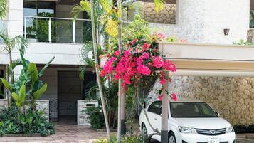 A white car parked in front of a building with a stone facade and a balcony.