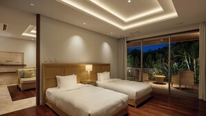 Une chambre d’hôtel avec deux lits, une table de chevet, une lampe, un canapé et une vue sur l’extérieur.
