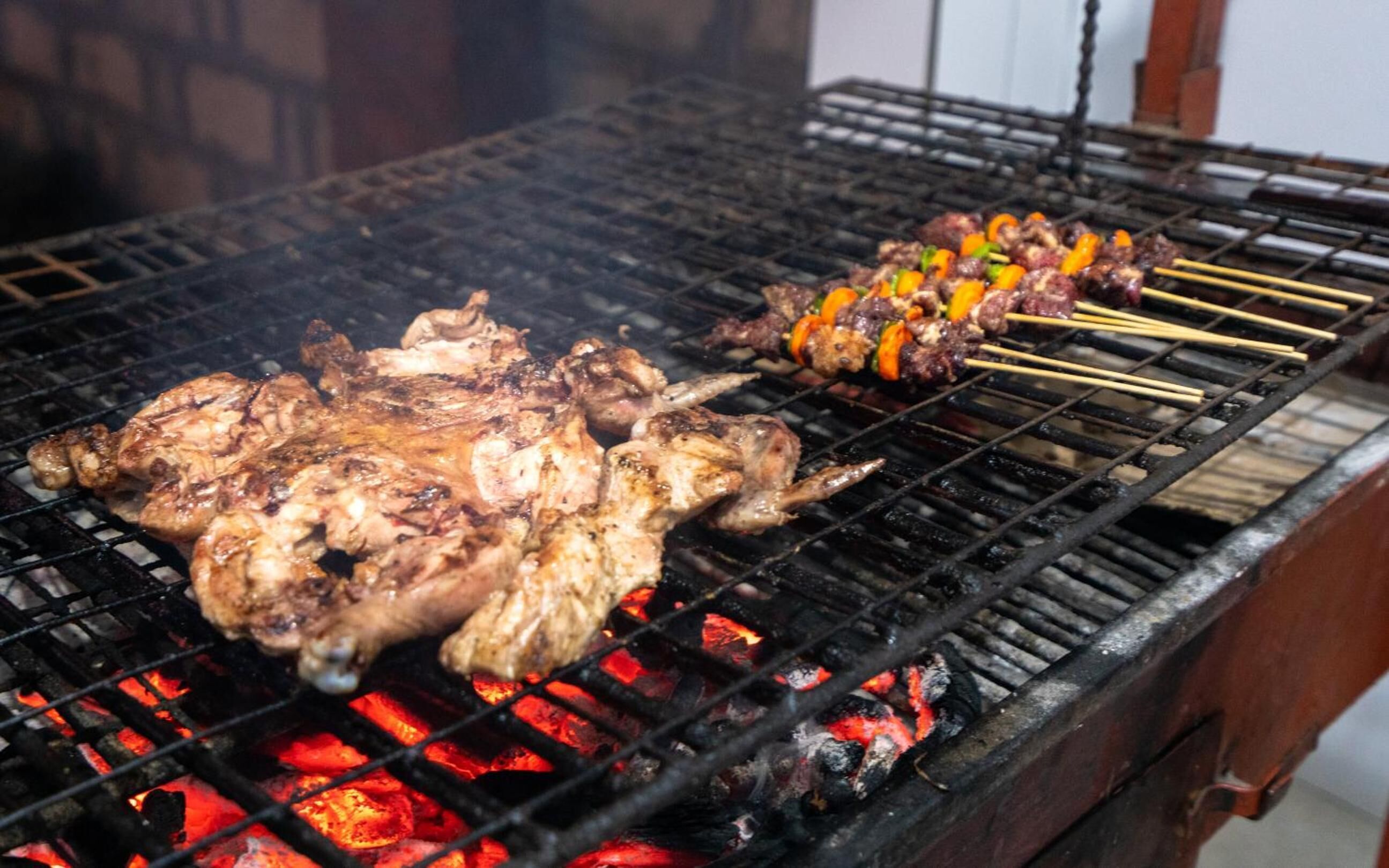 En grill med forskellige kødtyper og grøntsager, der tilberedes.