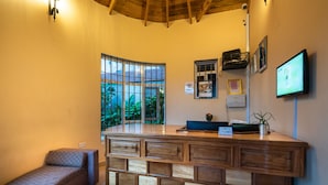 Un área de recepción con mostrador de madera, una pequeña zona de estar y un ventanal con vistas a zonas verdes.