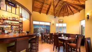 Zona de bar con mobiliario de madera y vistas a la montaña a través de las ventanas.