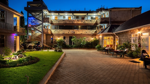 Un patio con un sendero de ladrillo, una zona de comedor con mesas y sillas, y un edificio de varios pisos con balcones.
