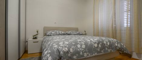 A bedroom with a bed, nightstand, and a small table with a lamp.