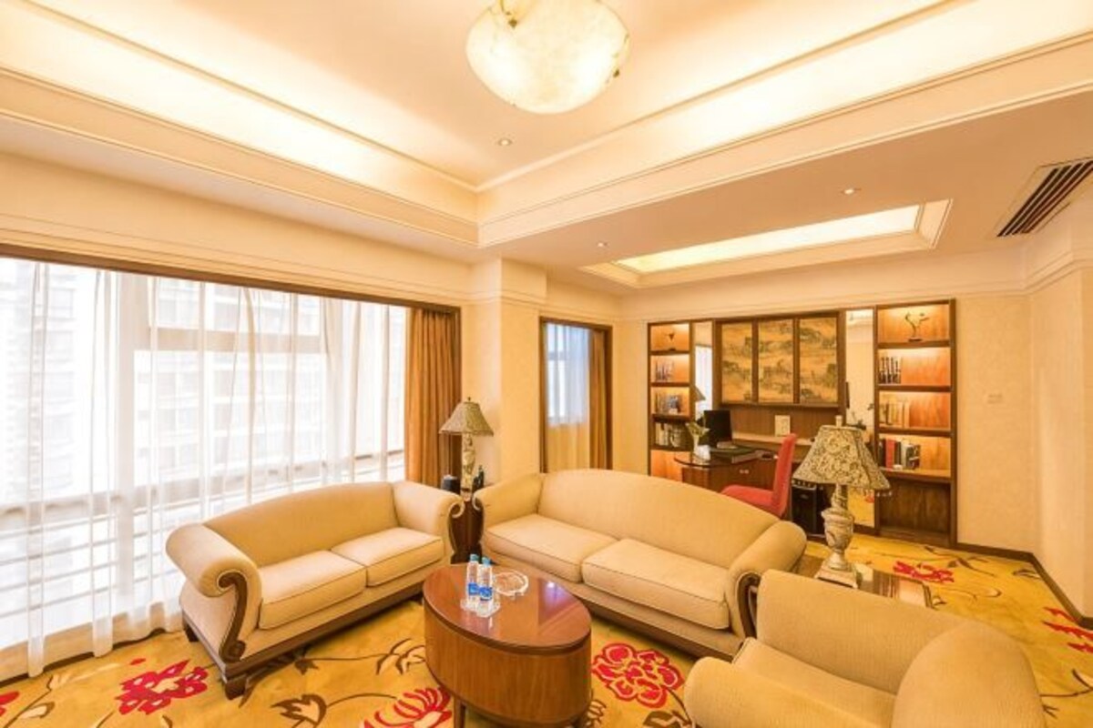 A hotel living room with a sofa set, a coffee table, and a bookshelf.