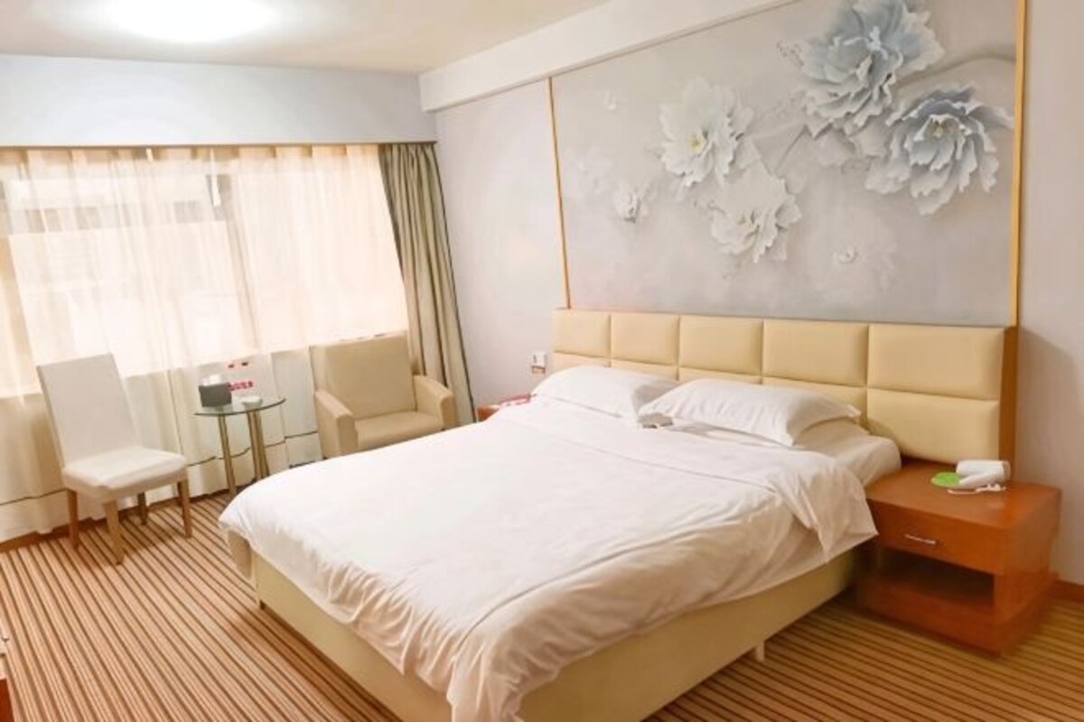 A hotel room with a large bed, a small round table, a chair, and a nightstand.