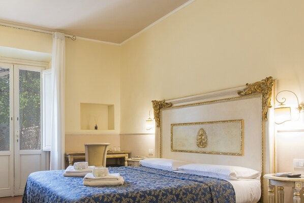 Een hotelkamer met een groot bed, een bureau, een stoel en een raam met gordijnen.