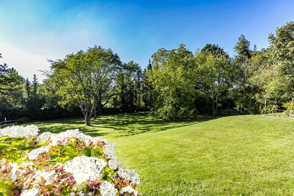 A well-maintained grassy area with trees and a flower bed in the foreground. - Hotel Villa Falkenberg (Düsseldorf)