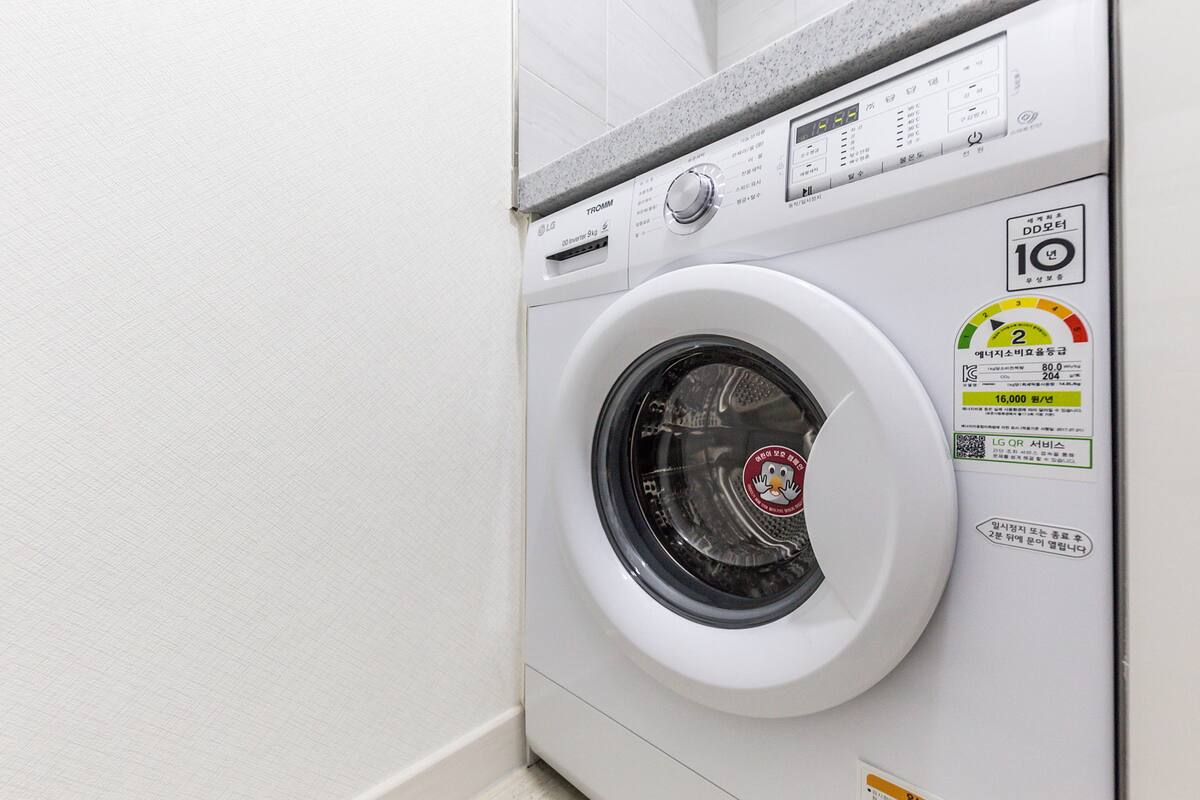 A front-loading washing machine with a digital control panel, a water level indicator, and a QR code.