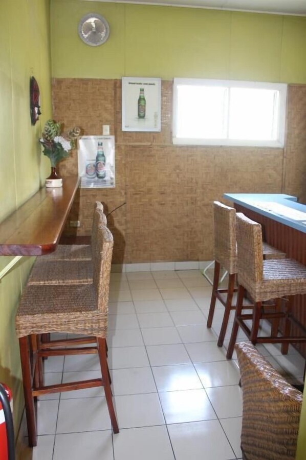 Una cocina con una encimera larga, sillas de mimbre y un refrigerador.