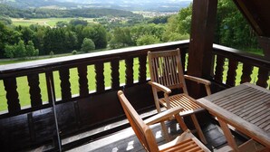 Eine Holzdielen-Terrasse mit Blick auf eine grüne Landschaft und Berge.