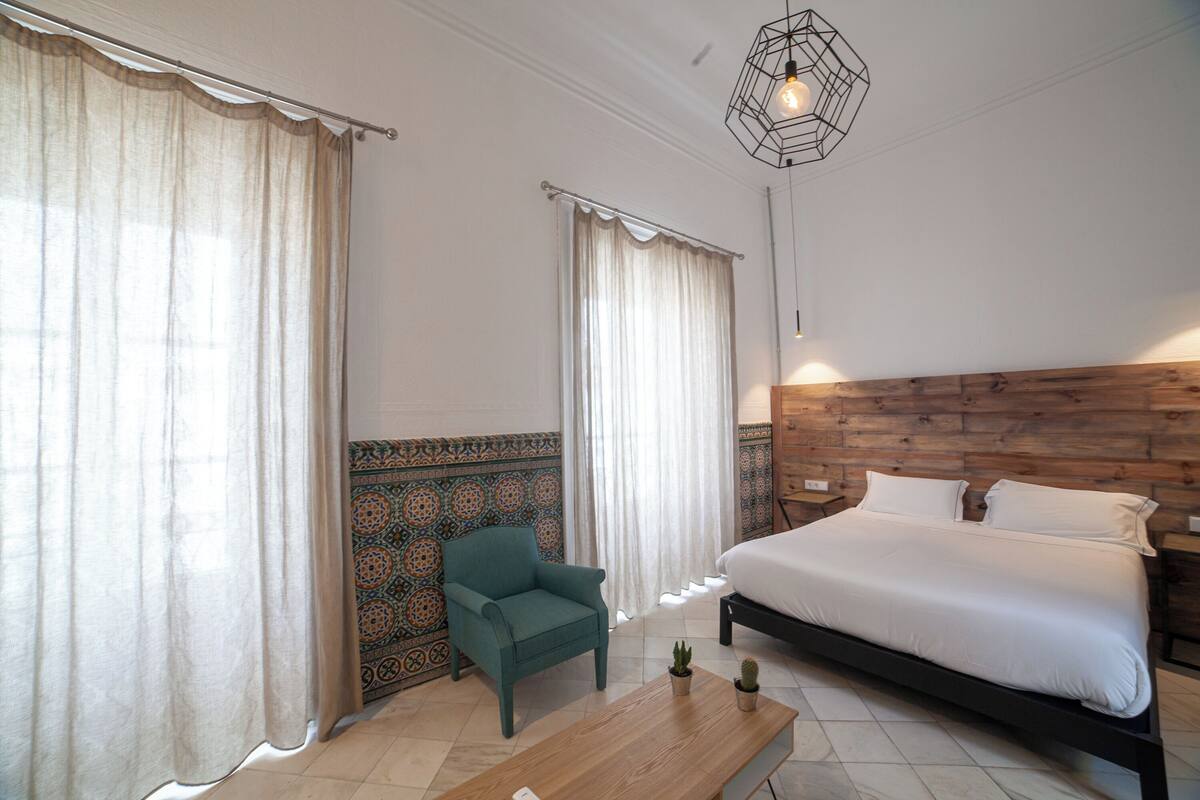 A bedroom with a bed, a chair, a table, and a decorative wall.