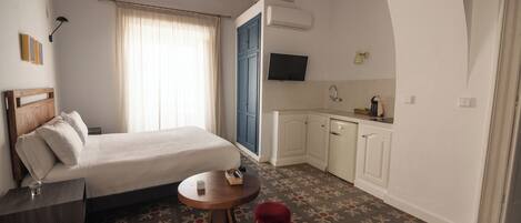 A bedroom with a bed, bedside table, and a small round table with a stool.