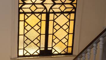 Una ventana de vitral con diseño geométrico, una pared de mármol y una barandilla blanca.