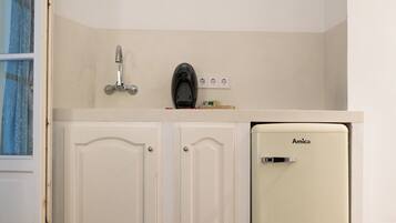 A compact kitchenette with a white cabinet, a sink, and a small refrigerator labeled 'Amica'.