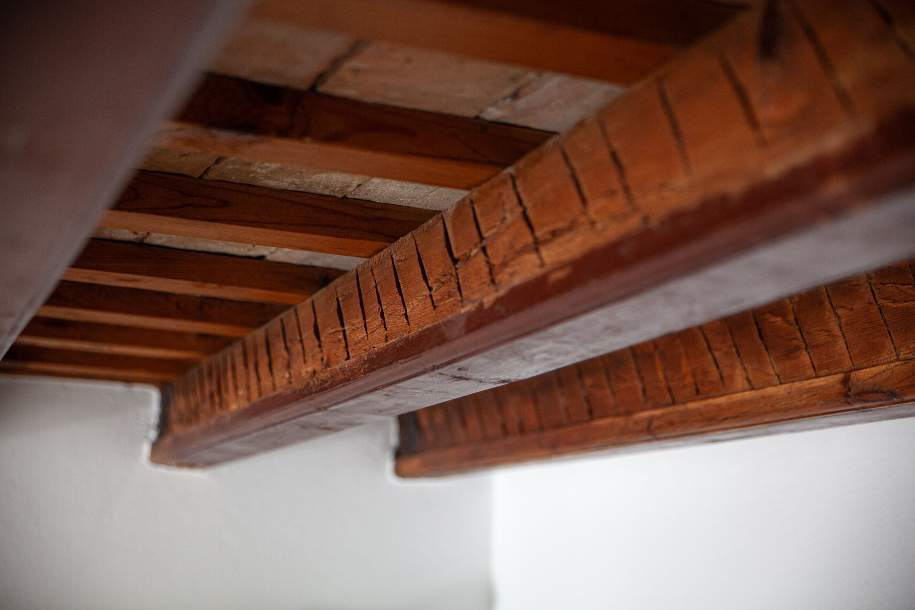 Un primo piano di un soffitto in legno con travi a vista e mattoni.