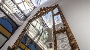 A grand hall with ornate mirrors, a skylight, and a balcony with railings. - Siglo XIX (Tarifa)