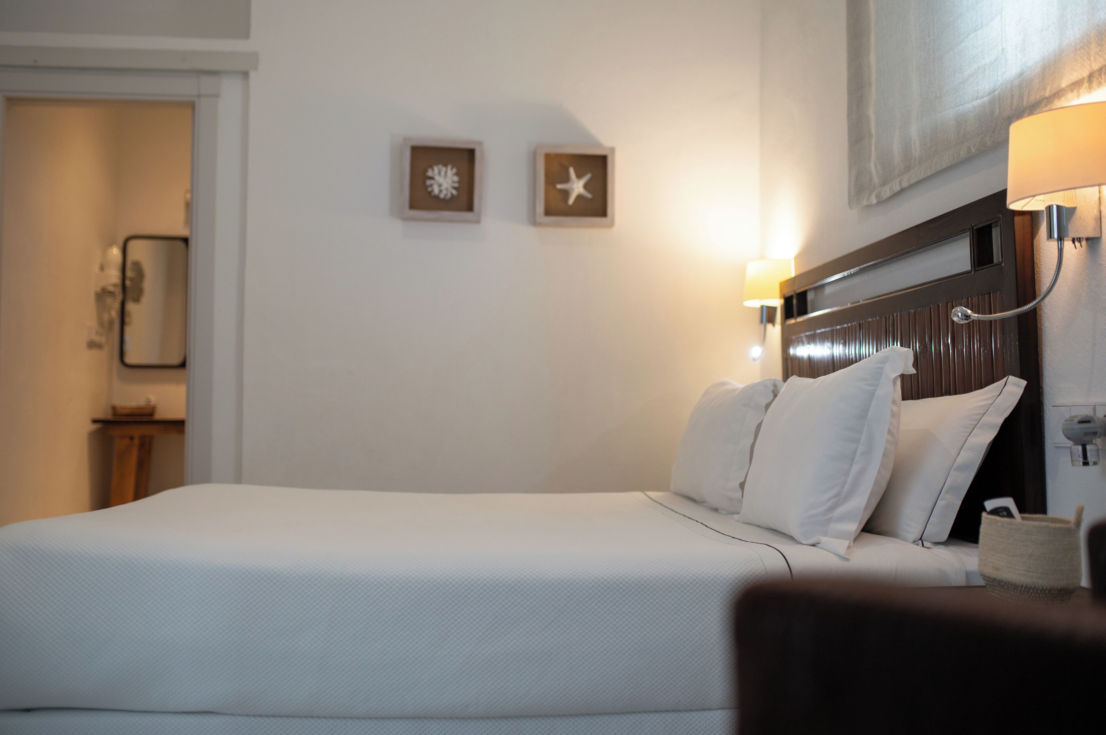 Une chambre d’hôtel comprenant un lit, une table de chevet, une lampe et deux décorations murales en forme d’étoiles de mer.