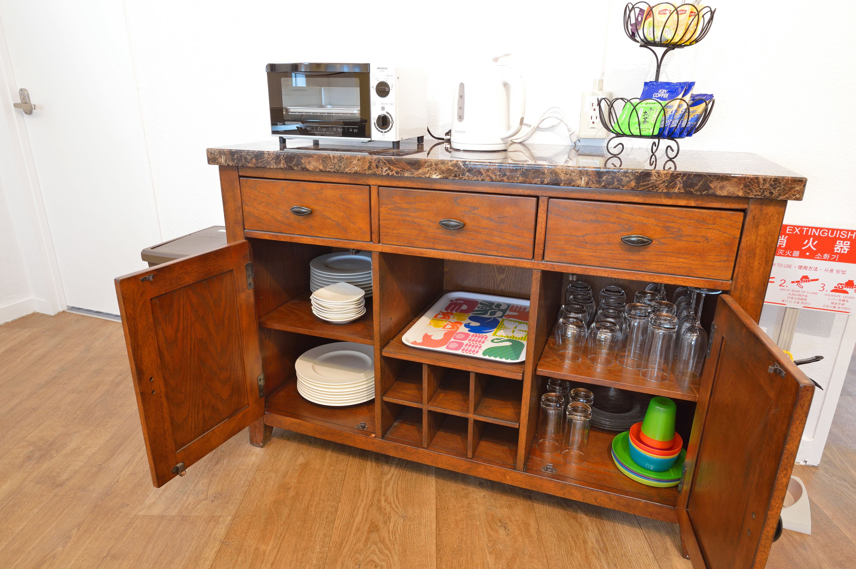 Een houten keukenkastje met een magnetron, een koffiezetapparaat en een decoratief object erboven.