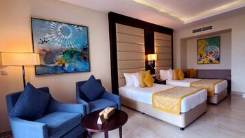 A hotel room with two beds, a sofa, a coffee table, and two paintings.