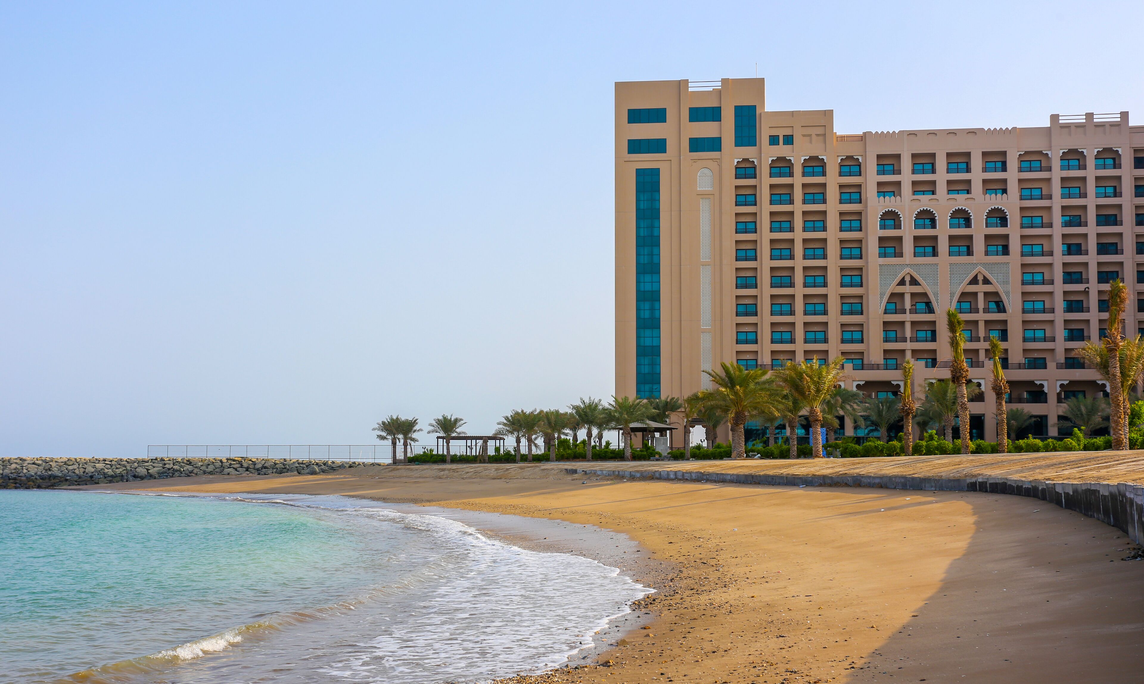 Hotel frente al mar con diseño moderno, que destaca por una torre vertical imponente y múltiples balcones.