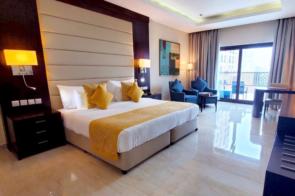 Une chambre d’hôtel avec un grand lit, des tables de chevet, un bureau, une chaise et un téléviseur.
