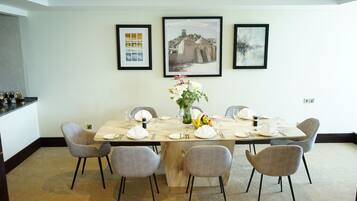 Un coin repas avec une longue table dressée pour six personnes, entourée de six chaises. Trois tableaux encadrés sont accrochés au mur, au-dessus de la table.