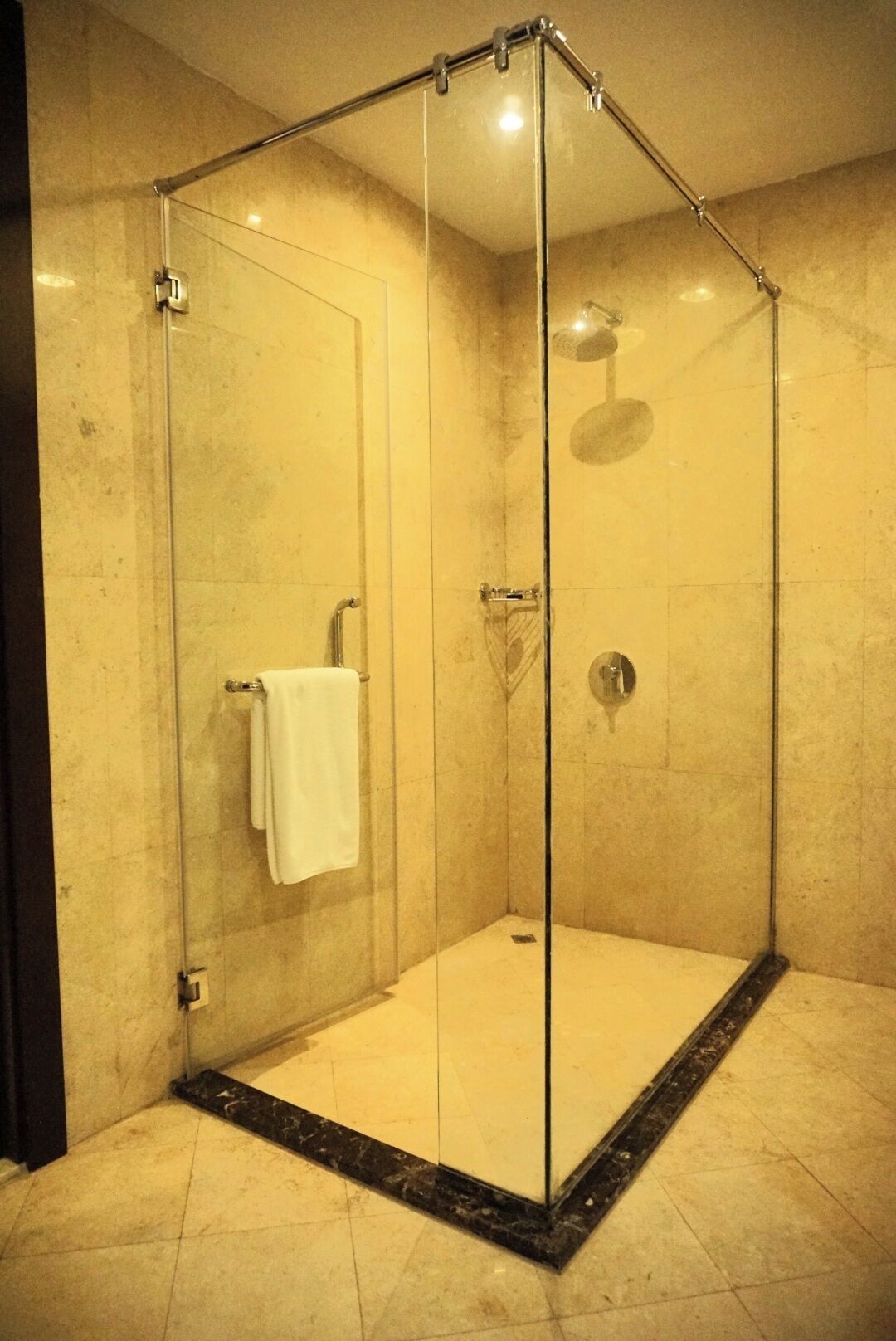 A glass-enclosed shower with a white towel hanging on the door.