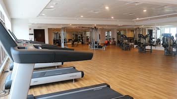 Un gimnasio con cintas de correr, máquinas de pesas y un espejo grande.