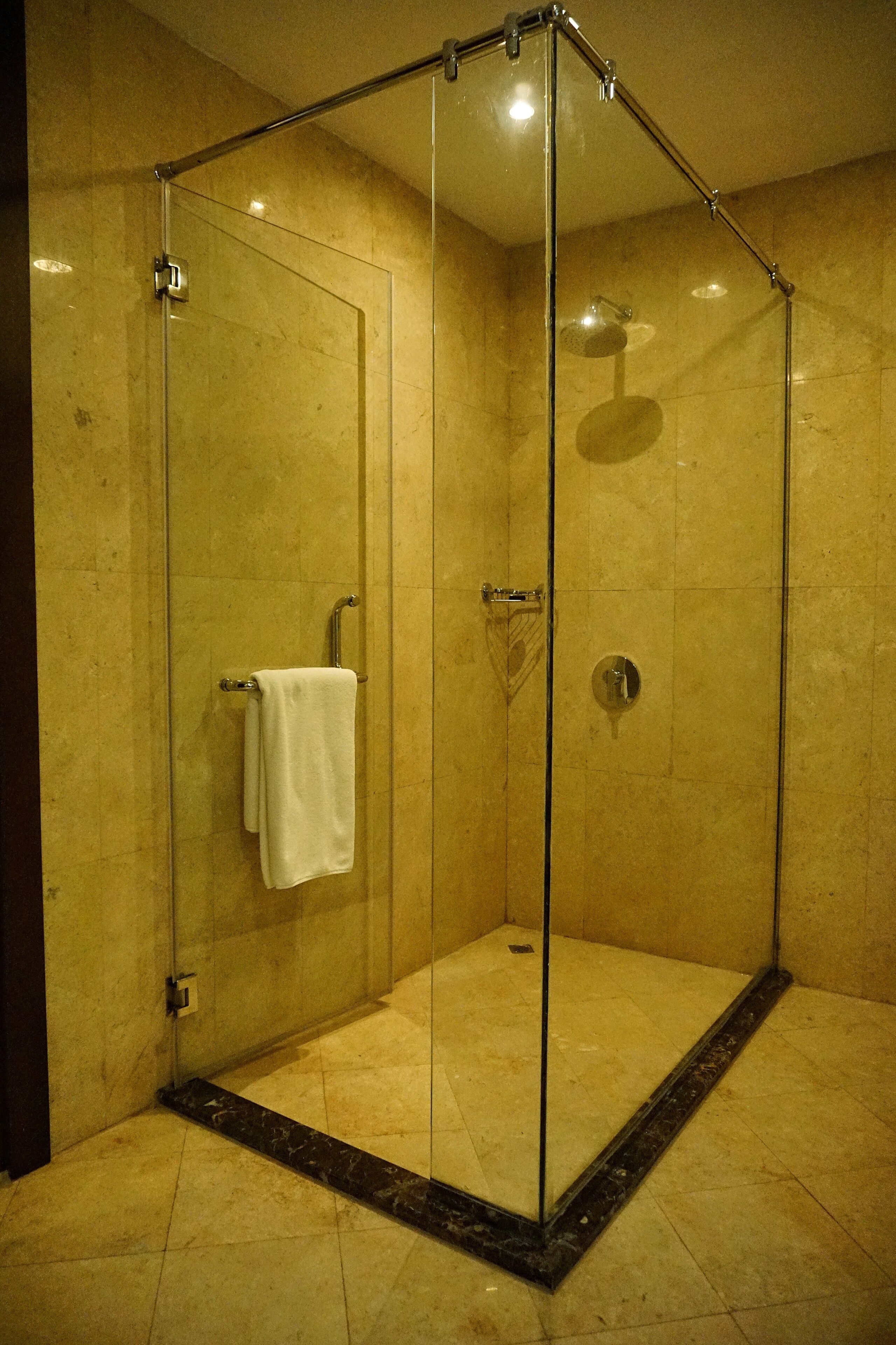 A glass-enclosed shower with a white towel hanging on the door handle.