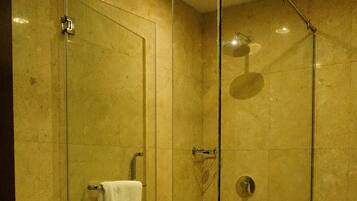 A glass-enclosed shower with a white towel hanging on the door handle.