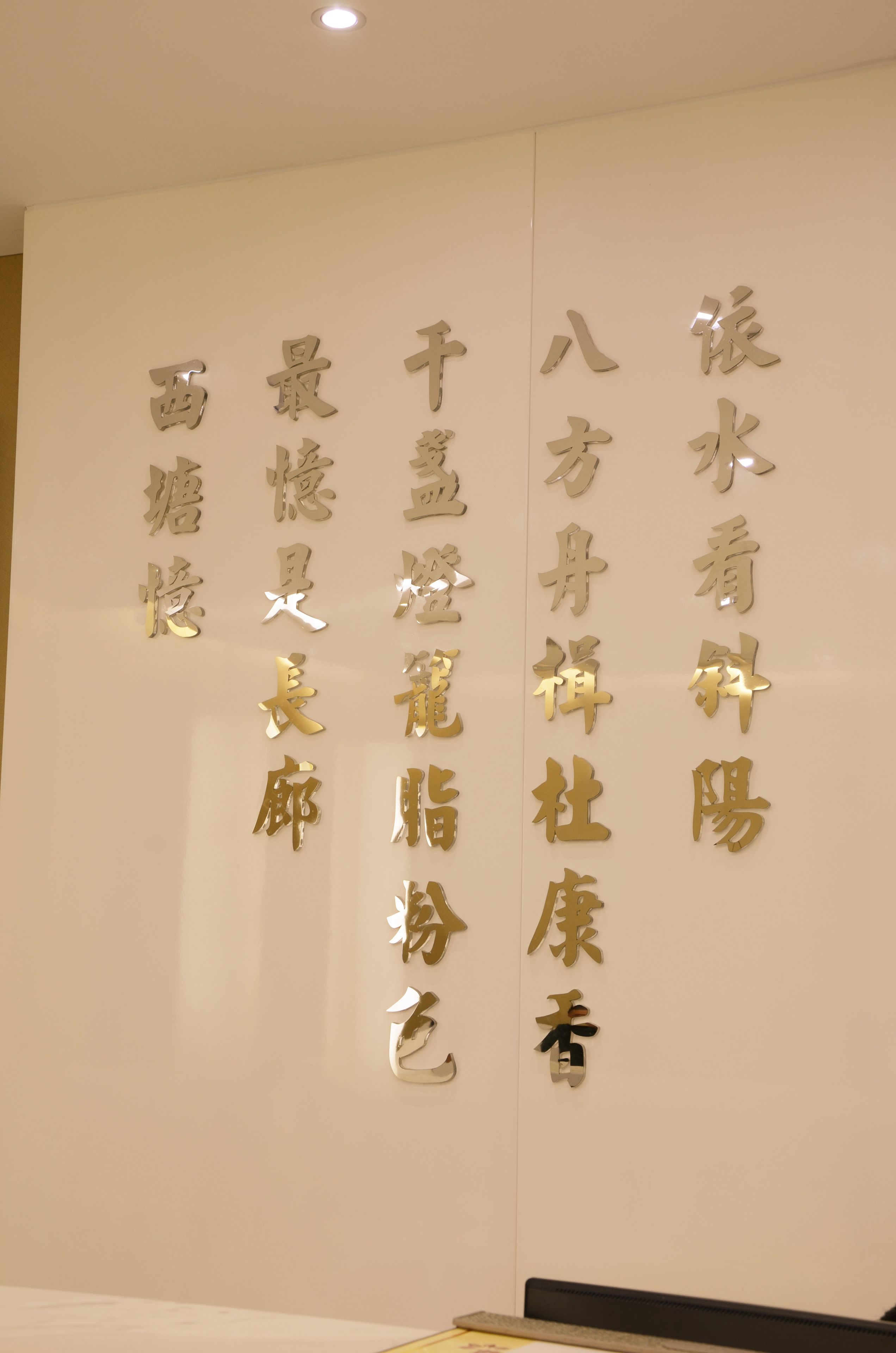 Una pared con caracteres chinos dorados, probablemente indicando el nombre o tema del lugar.