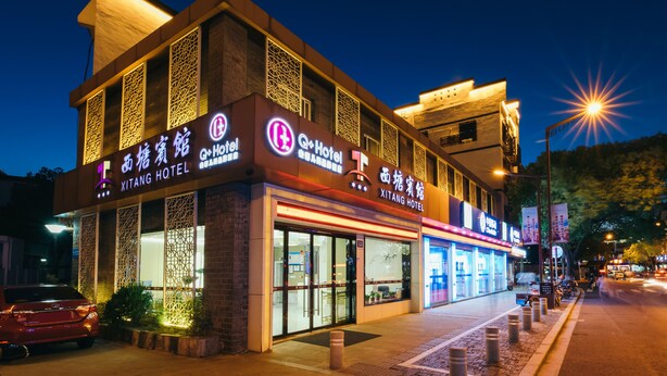A hotel with a modern facade, large glass windows, and a prominent signage. - Xitang Hotel (Jiaxing)