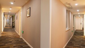 A hotel hallway with carpeted floors, recessed lighting, and framed pictures on the walls. - Xitang Hotel (Jiaxing)