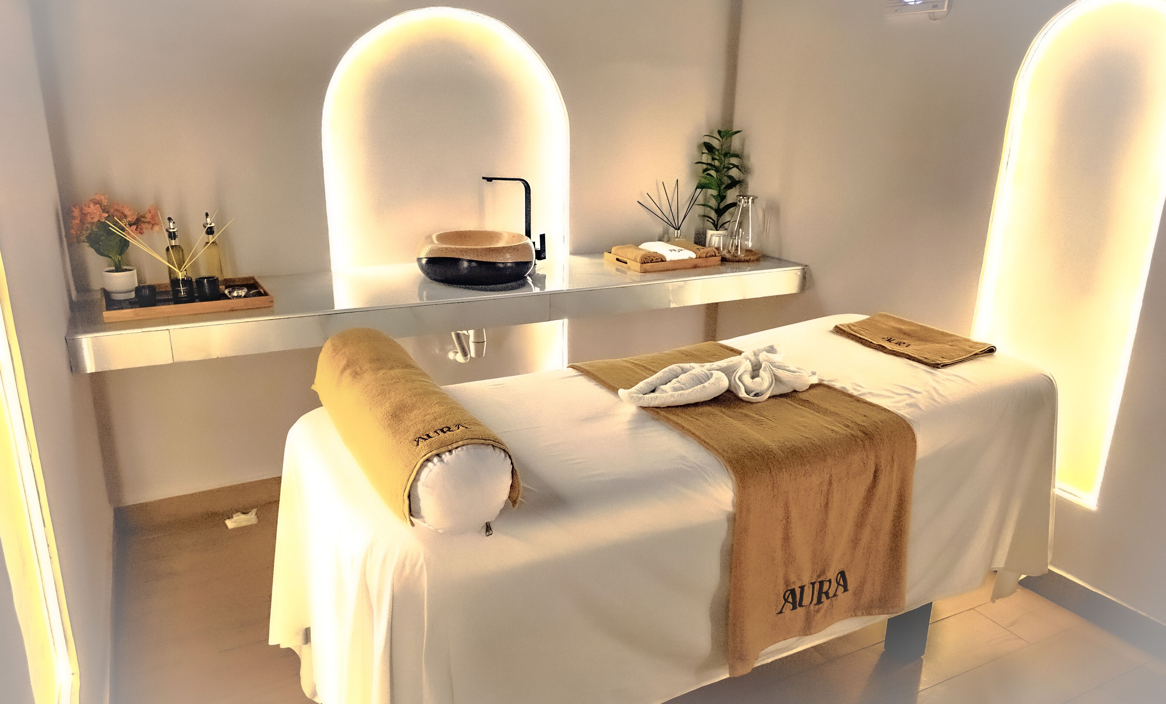 A spa room with a massage table, a shelf with toiletries, and a small plant.