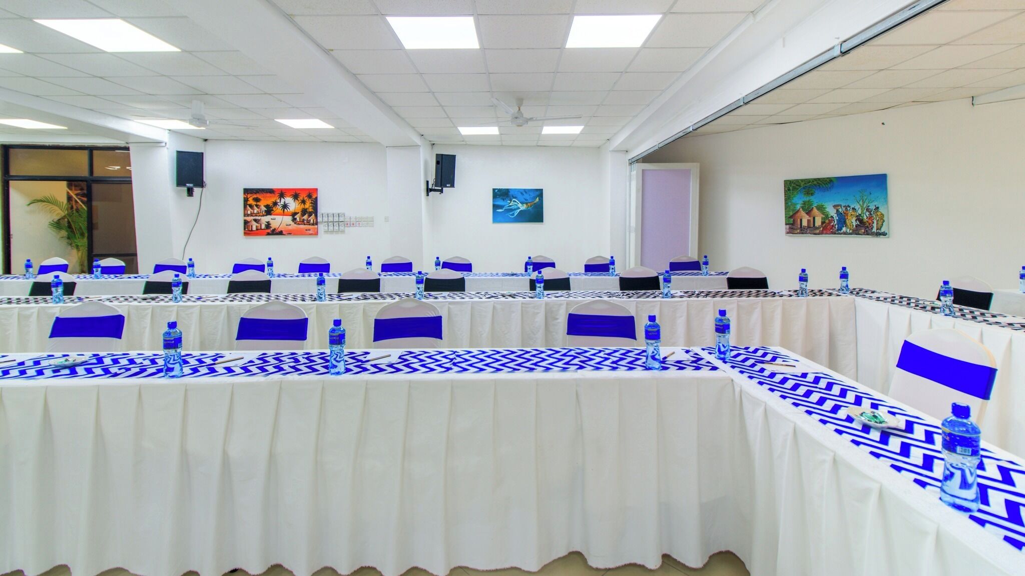 A conference room with tables set for meetings, white walls, and ceiling lights.