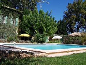 Una piscina al aire libre de temporada, sombrillas