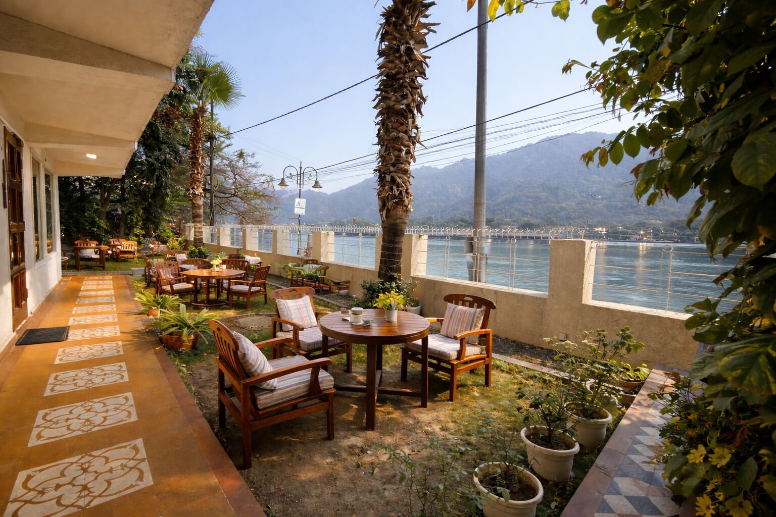 A terrace with outdoor seating, a view of the water, and mountains in the background.