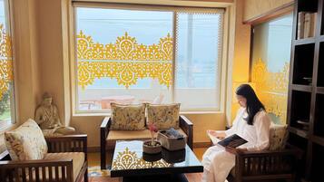 A room with a Buddha statue, a sofa, a table with a decorative tray, and a bookshelf.