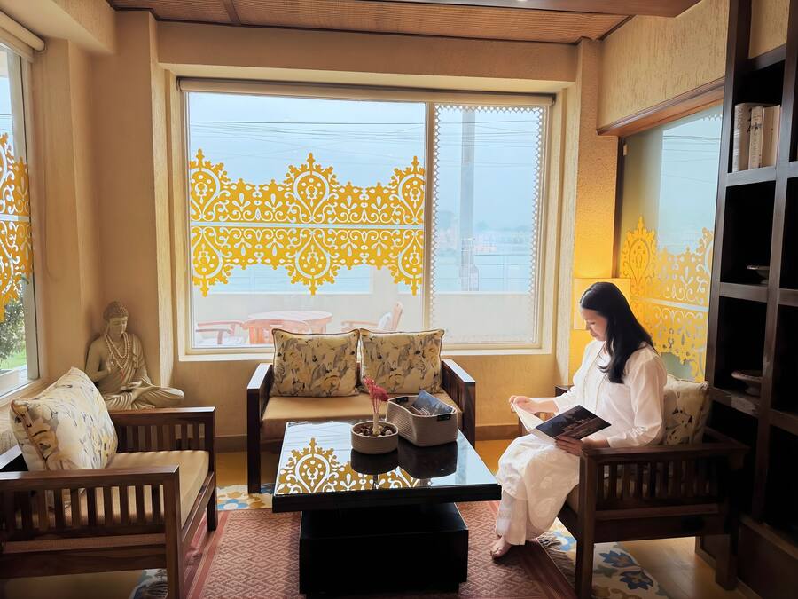 A room with a Buddha statue, a sofa, a table with a decorative tray, and a bookshelf.