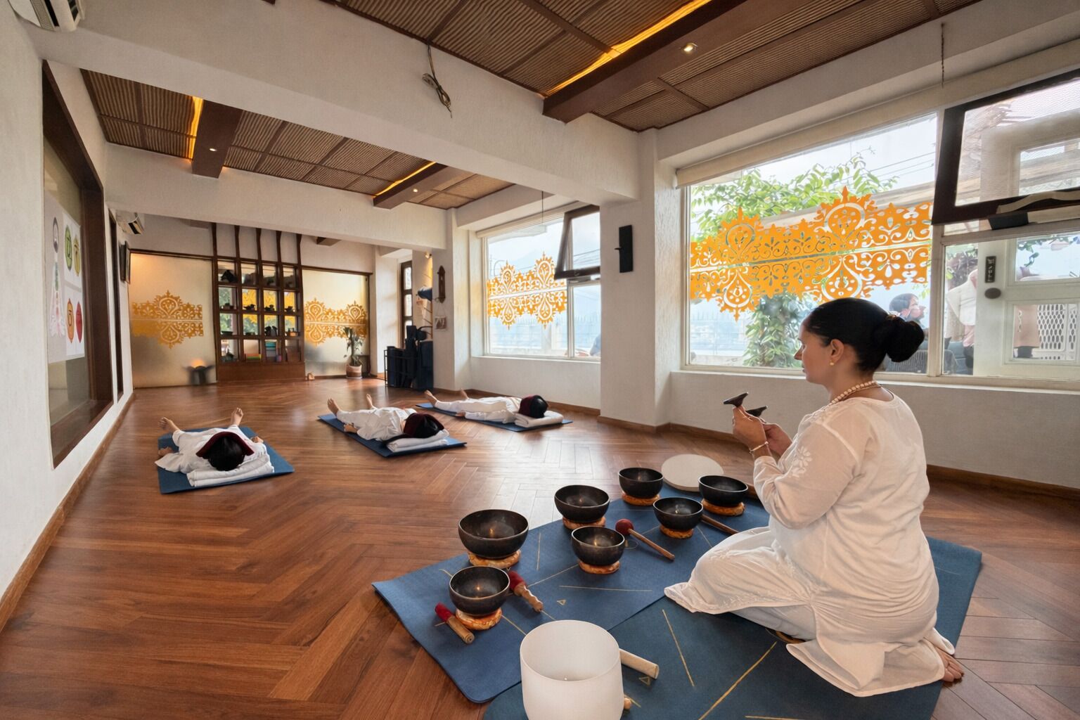 Un estudio de yoga con pisos de madera, ventanas amplias y un ambiente tranquilo.