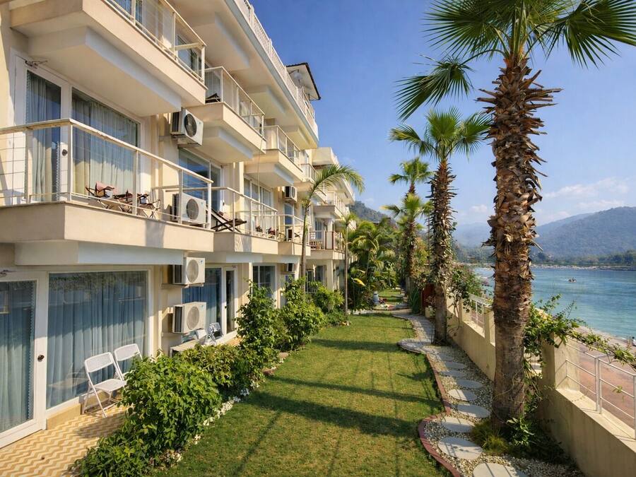 A multi-story hotel with balconies, air conditioning units, and a view of a body of water with palm trees.